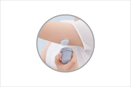二の腕の後ろ側にセンサーを貼り、装着用の器具を外しているところ
